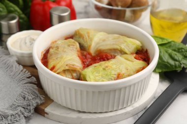 Lezzetli dolgulu lahana ruloları ve malzemeler masada, yakın plan.