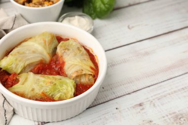 Doldurulmuş lahanalar hafif ahşap masada kasede yuvarlanıyor, yakın plan. Metin için boşluk