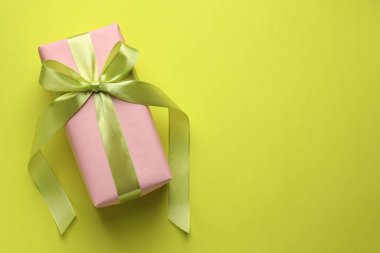 Açık yeşil arka planda fiyonklu paketlenmiş hediye, üst manzara. Metin için boşluk