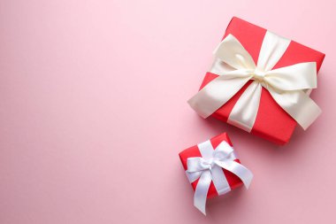 Açık pembe arka planda fiyonklu paketlenmiş hediyeler. Metin için boşluk