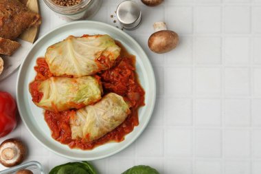 Lezzetli dolgulu lahana ruloları ve malzemeler beyaz fayanslı masada, düz yerde. Metin için boşluk