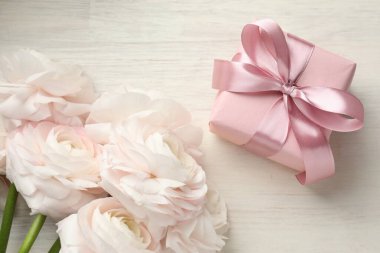 Güzel çiçekler ve hediye beyaz ahşap masada, düz yatıyordu.