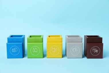 Çocuklar için çöp ayıklama oyunu seti. Açık mavi arkaplanda parlak ahşap çöp kutuları, yakın plan