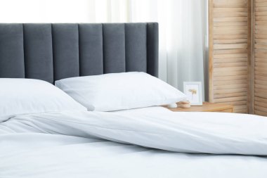 Yatak odasında temiz beyaz çarşafları olan rahat bir yatak.