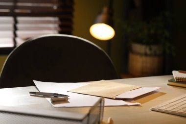 Zarfın içinde mektup, kağıt ve kalem, kapalı masa, yakın plan.