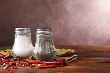 Ahşap masada baharatlı tuzluk ve biberlikler, yakın plan. Metin için boşluk