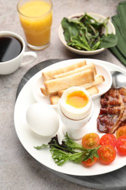 Gri masada servis edilen kaynamış yumurta ve pastırmalı lezzetli bir kahvaltı.