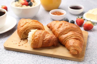 Nefis bir kahvaltı. Lezzetli kruvasanlar, reçel, böğürtlen, yulaf ezmesi ve kahve açık gri masada, yakın plan.