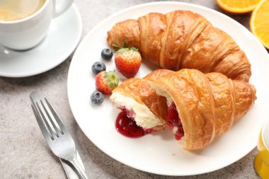 Nefis bir kahvaltı. Açık gri masada reçelli, dutlu ve kahveli lezzetli kruvasanlar, yakın plan.