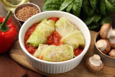 Lezzetli dolgulu lahana ruloları ve malzemeler masada, yakın plan.