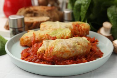 Yummy stuffed cabbage rolls served on white tiled table, closeup