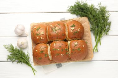 Sarımsaklı taze çörekler ve beyaz ahşap masa üzerinde dereotlar.