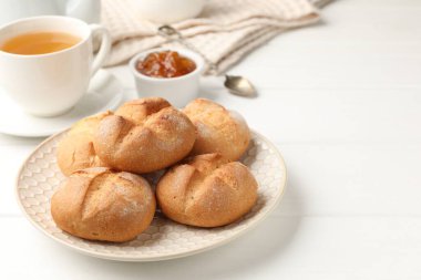 Taze çörekler, reçel ve çay beyaz ahşap masada, yakın plan. Metin için boşluk