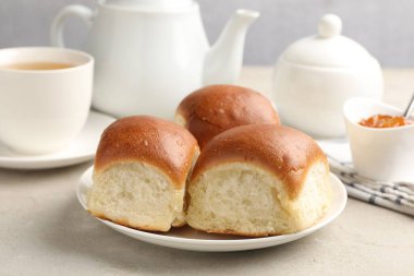 Taze çörekler, reçel ve çay ışık masasında, yakın plan.