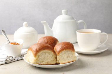 Fresh buns, jam and tea on light table