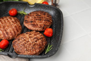 Lezzetli ızgara et köfteleri, domatesler ve ızgara tavada biberiye, beyaz fayanslı masa, yakın çekim. Metin için boşluk