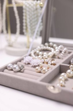Beyaz masadaki kutuda farklı tarz mücevherler, yakın plan.