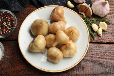 Kasede sarımsak turşusu, taze sebzeler ve ahşap masada aromatik baharatlar.