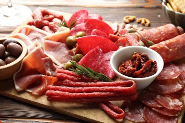 Farklı pişirilmiş et, sosis ve zeytin içeren ahşap masa, yakın plan.