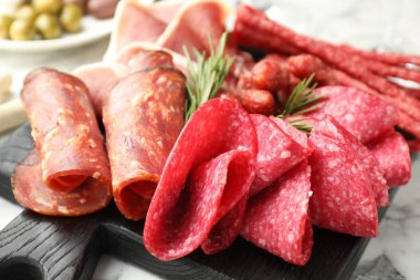 Şarküteri tahtası beyaz mermer masa üzerinde farklı pişirilmiş et ve sosisler, yakın plan.