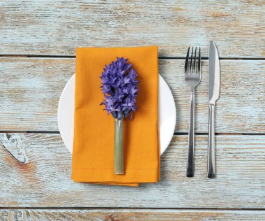 Ahşap arka planda çiçek dekoru olan şık masa ayarları, düz yatış