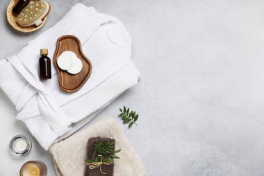 Açık gri arka planda bornozla düz kompozisyon ve spa gereksinimleri vardı. Metin için boşluk