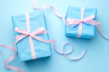 Açık mavi arka planda fiyonklu paketlenmiş hediyeler.