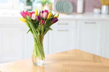 İçerideki ahşap masada vazodaki renkli lalelerden oluşan bir buket. Metin için boşluk