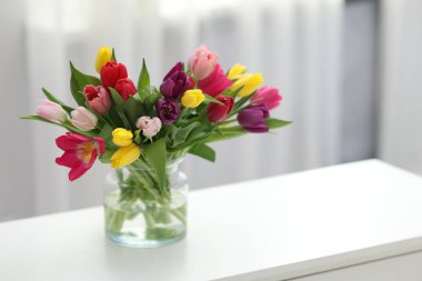 Beyaz masadaki vazodaki renkli lalelerden oluşan güzel bir buket. Metin için boşluk