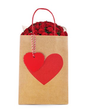 Kırmızı gül buketi, beyaz arka planda kırmızı kalpli kağıt torbada. Romantik hediye.