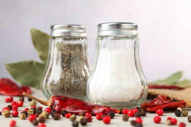 Açık gri masada baharatlı tuzluk ve biberlikler, yakın plan.