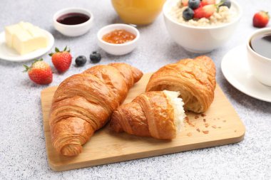 Nefis bir kahvaltı. Lezzetli kruvasanlar, reçel, böğürtlen, yulaf ezmesi ve kahve açık gri masada, yakın plan.