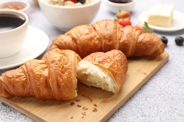 Nefis bir kahvaltı. Lezzetli kruvasanlar, böğürtlenler, yulaf ezmesi ve kahve açık gri masada, yakın plan.