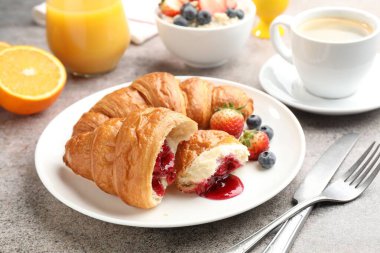 Nefis bir kahvaltı. Reçelli lezzetli kruvasanlar, açık gri masada böğürtlen ve içecekler, yakın plan.