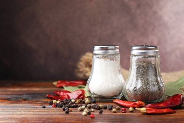 Ahşap masada baharatlı tuzluk ve biberlikler, yakın plan. Metin için boşluk