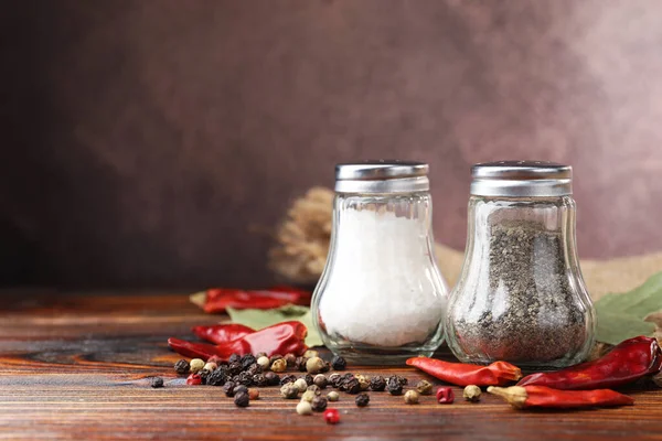 Ahşap masada baharatlı tuzluk ve biberlikler, yakın plan. Metin için boşluk