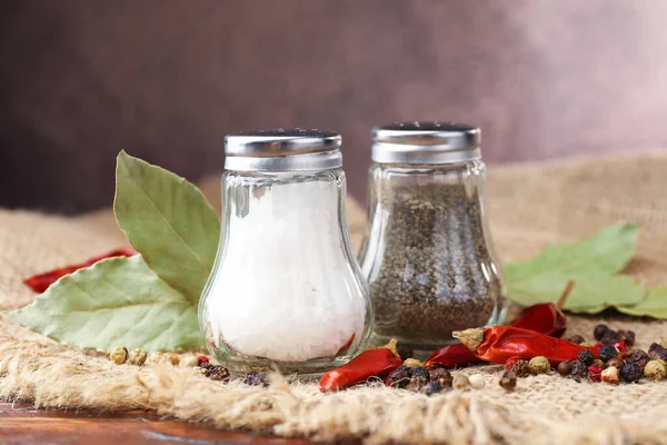 Ahşap masada baharatlı tuzluk ve biberlikler, yakın plan.
