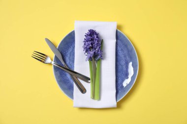 Sarı arka planda çiçek dekoru olan güzel masa ayarları, üst manzara.