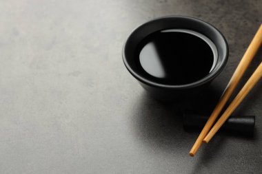 Soya sosu kasede ve çubuklar gri masada, yakın plan. Metin için boşluk