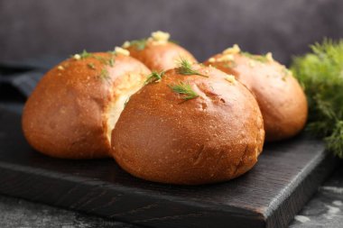 Siyah masada sarımsaklı taze çörekler ve dereotlar, yakın plan.