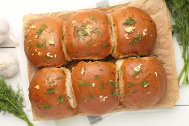 Sarımsaklı taze çörekler ve beyaz ahşap masa üzerinde dereotlar.