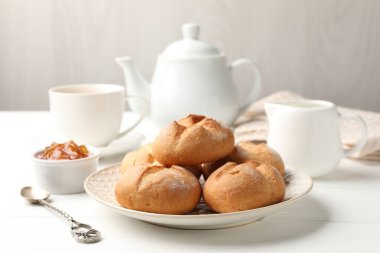 Taze çörekler, reçel ve çay beyaz ahşap masada.