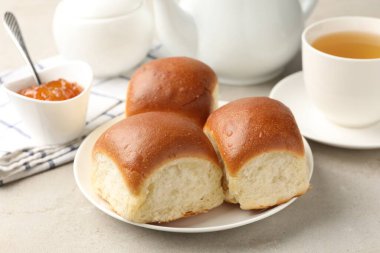 Taze çörekler, reçel ve çay ışık masasında, yakın plan.