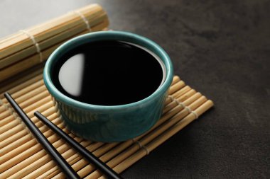 Soya sosu kasede ve çubuklar gri masada, yakın plan. Metin için boşluk