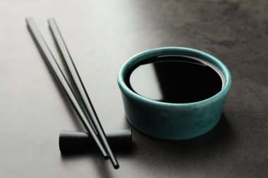 Soya sosu kasede ve çubuklar gri masada, yakın plan.