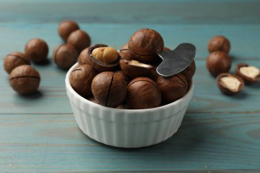 Macadamia cevizleri ve metal anahtar açık mavi ahşap masada, yakın plan.