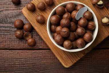 Macadamia fındıkları ve kasedeki metal anahtar tahta masada, düz yatıyordu.