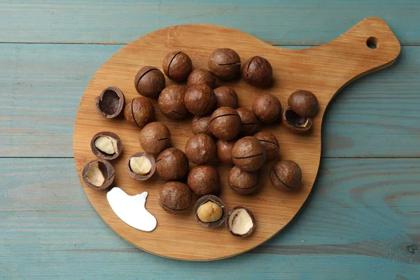 Macadamia fındığı ve metal anahtar açık mavi ahşap masa, üst görüş.