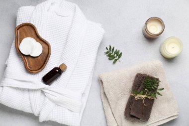 Flat lay composition with bathrobe and spa essentials on light grey background