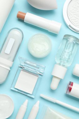 Açık mavi arka planda farklı makyaj ürünleri, düz yatış